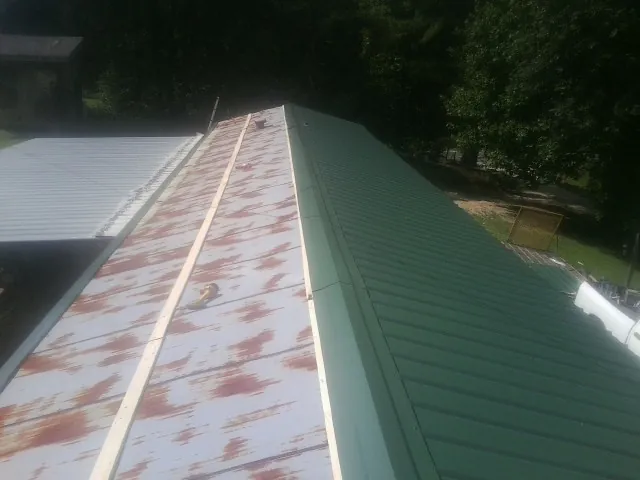 Old rusted panels beside newly installed green metal roofing — Wind Damage Roof Repair by Roofing Brothers in Syracuse